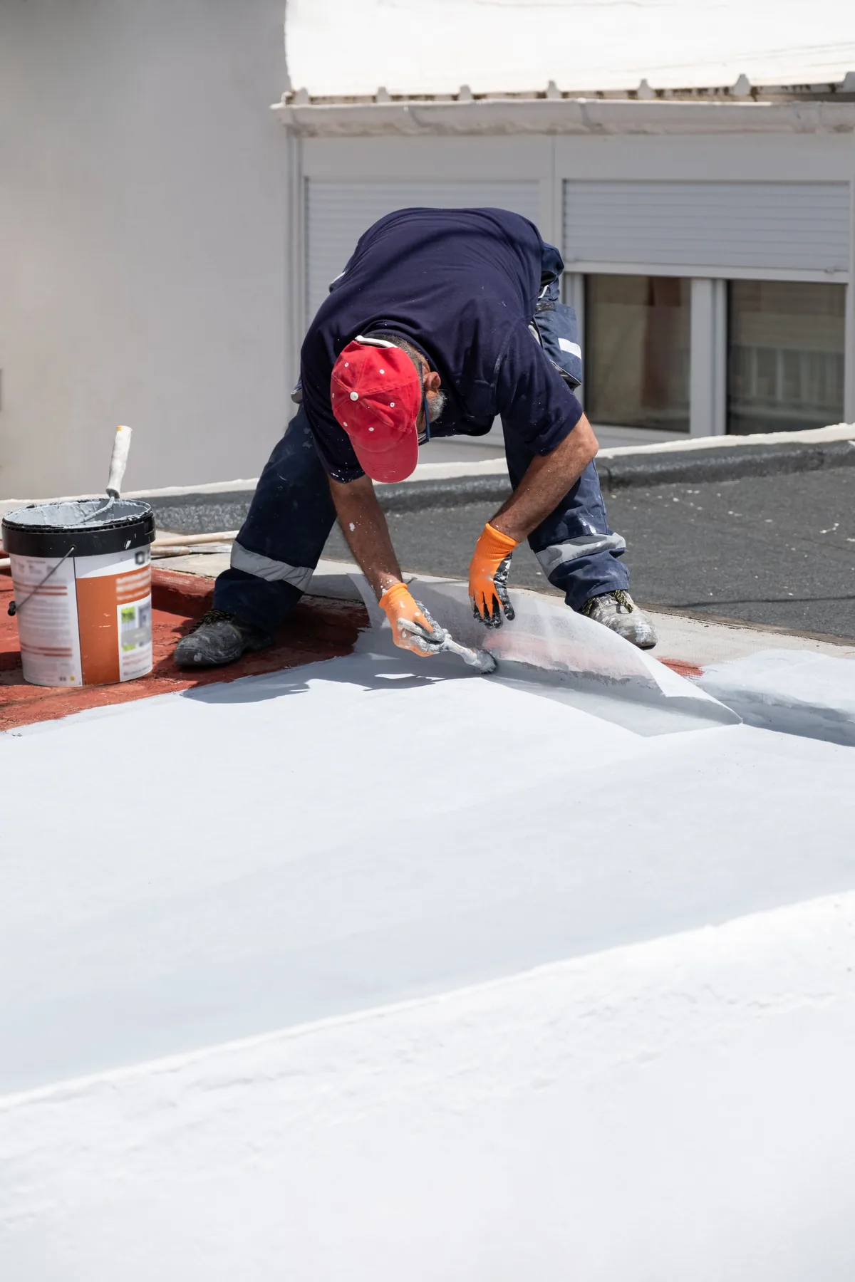 Trabajador aplicando impermeabilizante acrílico blanco en una azotea